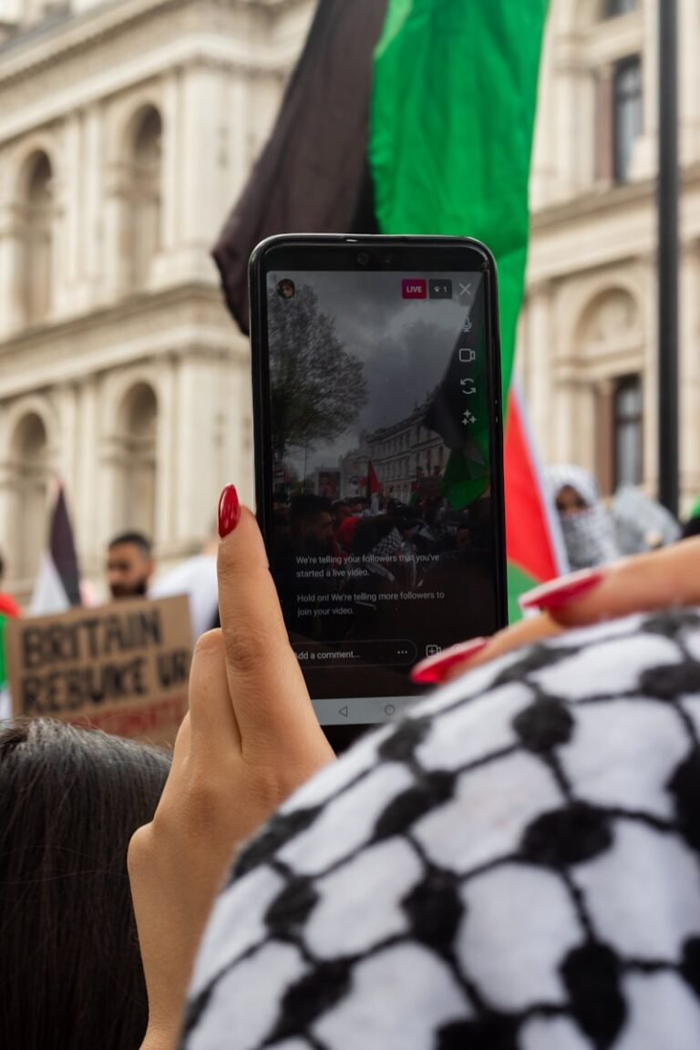 person holding black smartphone taking photo of people walking on street during daytime